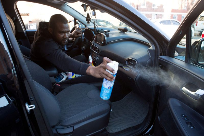 FILE PHOTO: Uber and Lyft driver Adama Fofana sprays disinfectant