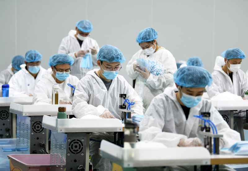 Employees work on a production line of surgical masks for