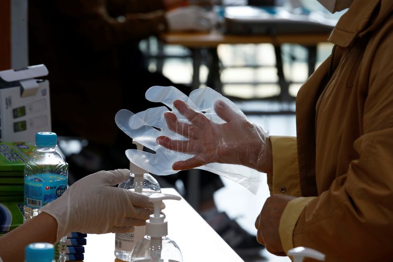 A woman dons plastic gloves to prevent contracting the coronavirus
