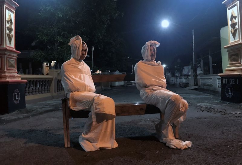 Volunteers Deri Setyawan and Septian Febriyanto sit on a bench