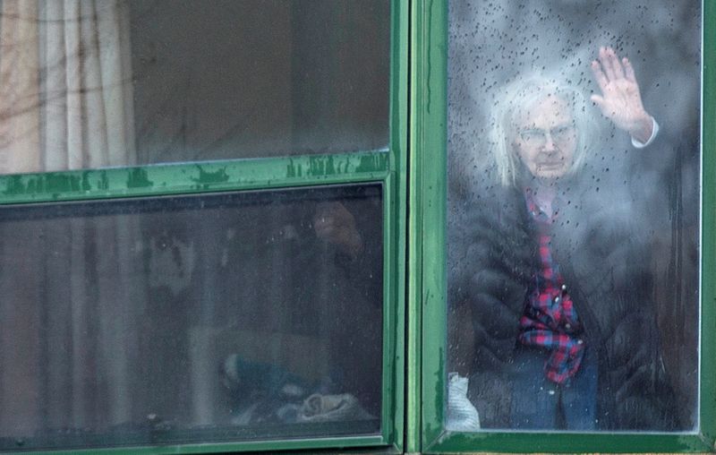 A resident waves from her window at a senior’s long-term