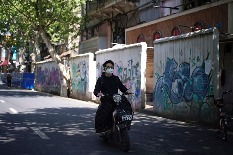 Man wearing a face mask rides an electric bicycle past