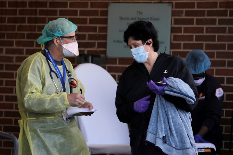 A healthcare worker speaks with a patient outside the emergency