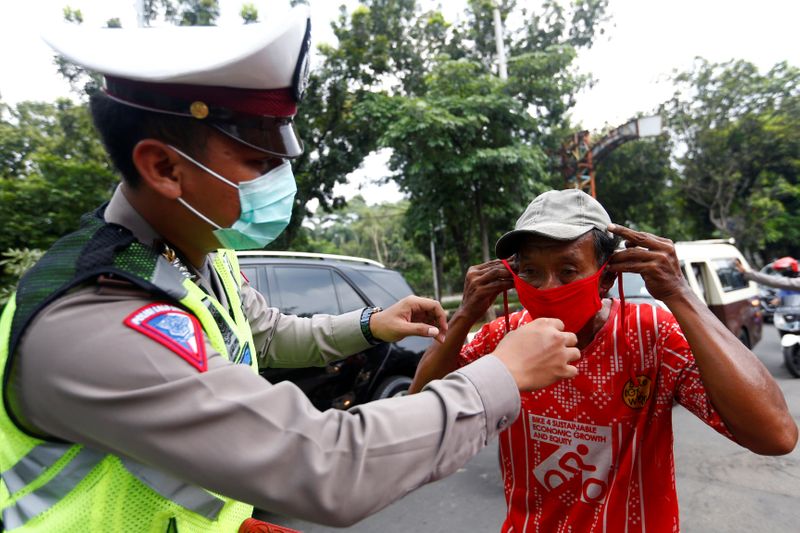 A police officer gives a face mask to a resident