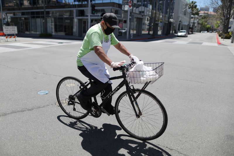 A food delivery driver cycles on an empty road as