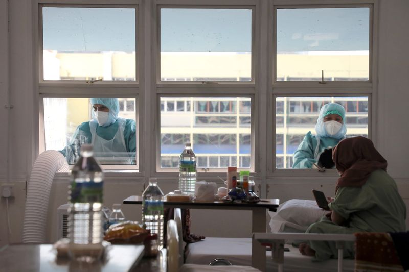 Workers wearing protective suits clean the windows outside the coronavirus
