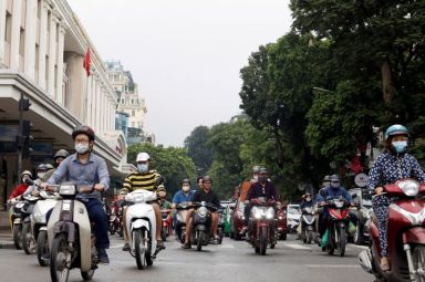 Residents wear protective face masks as they ride motorbikes on