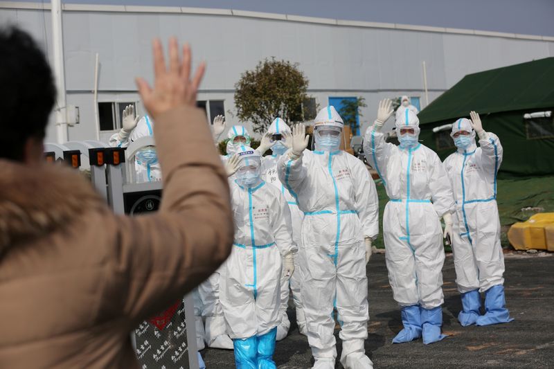 FILE PHOTO: Medical personnel in protective suits wave hands to