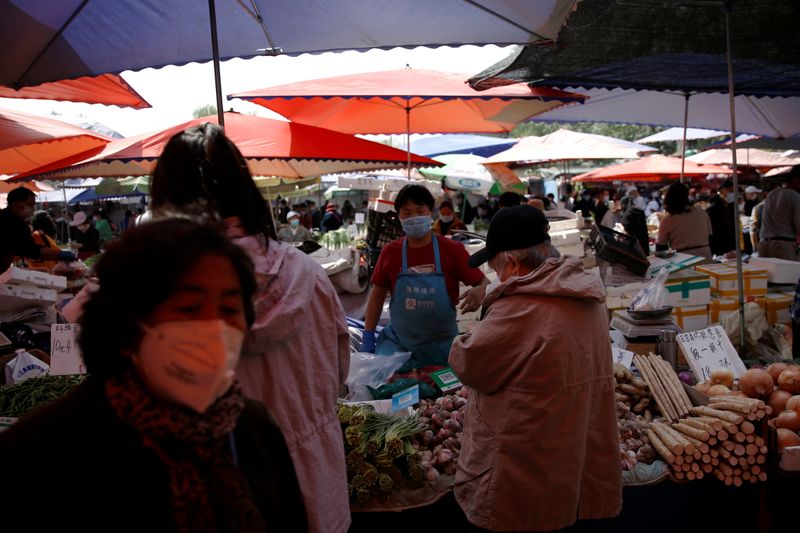 A vendor wearing a face mask attends to customers at
