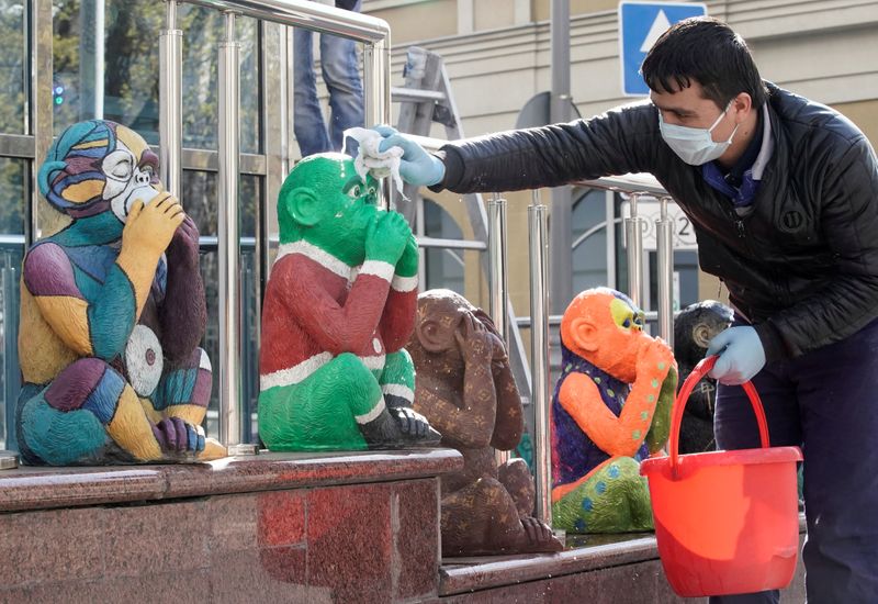 An employee wearing a protective mask washes figures outside a