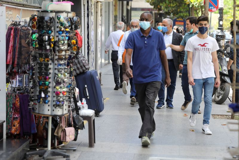 People wearing protective face masks walk past open shops in