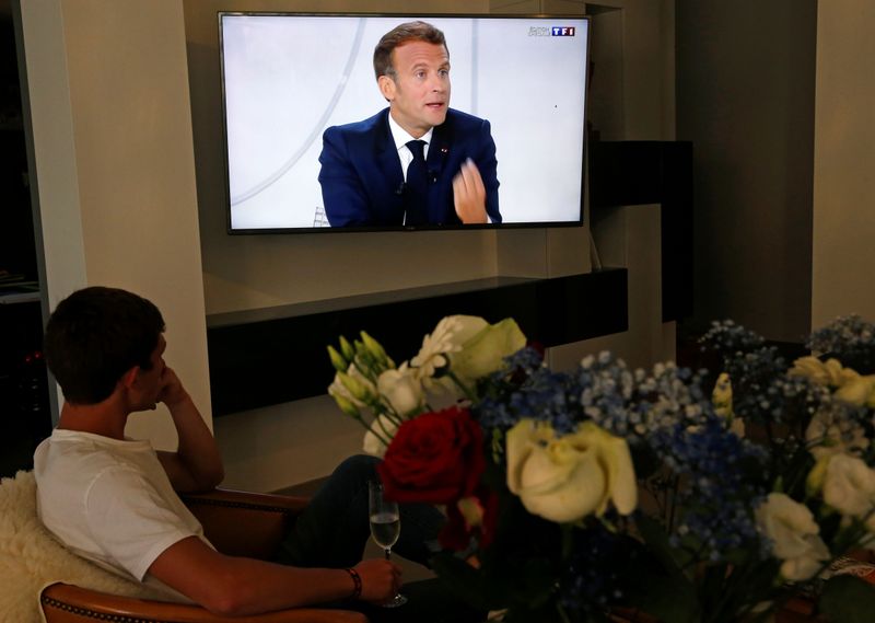 Man watches as French President Emmanuel Macron speaks during a
