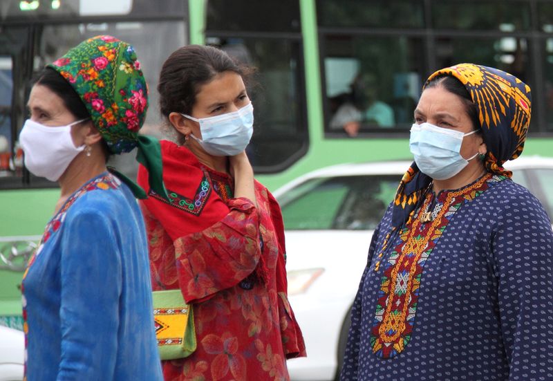 Women wearing protective face masks are seen at a bus