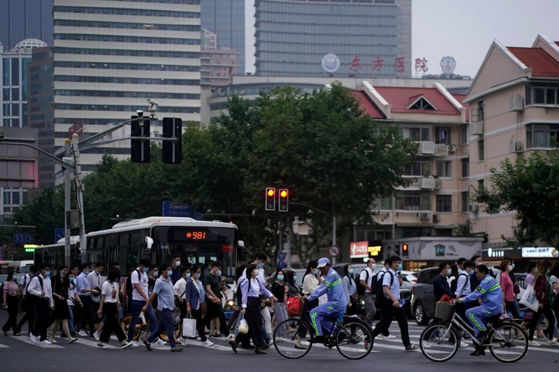 People wearing face masks walk on a street in Shanghai