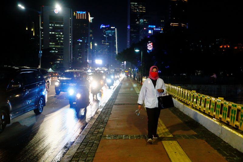 A woman wearing a protective face mask walks during rush