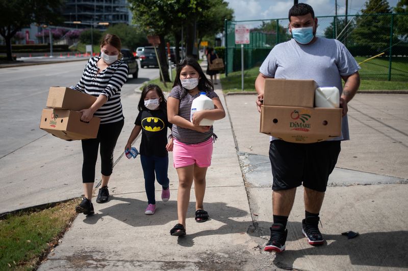 Members of the Rodriguez family carry groceries provided by the