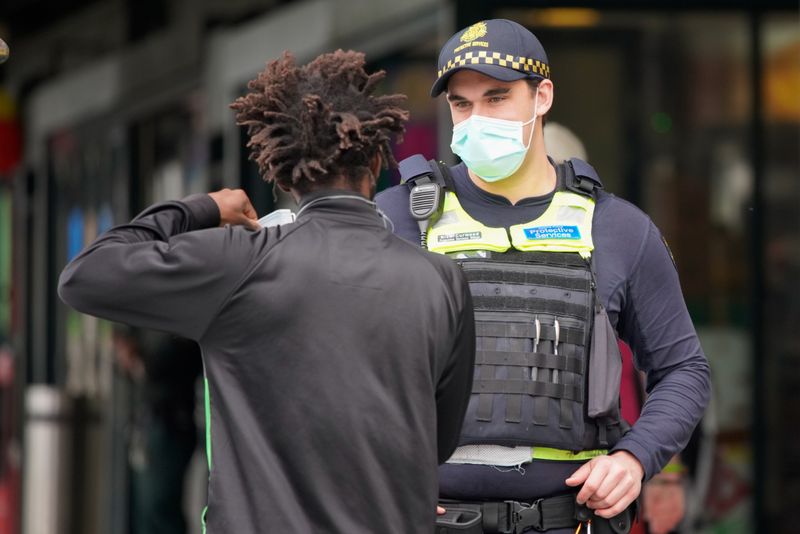 A Protective Services Officer wearing a face mask talks to