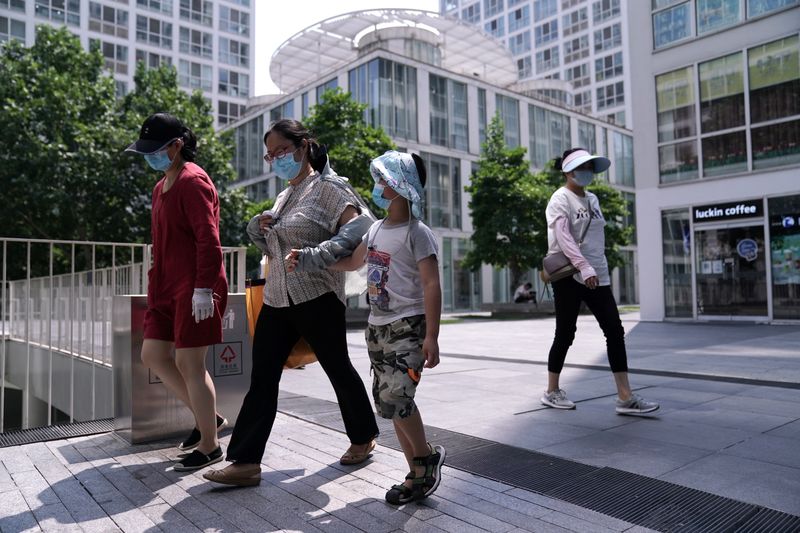 People wearing face masks walk past an office and commercial