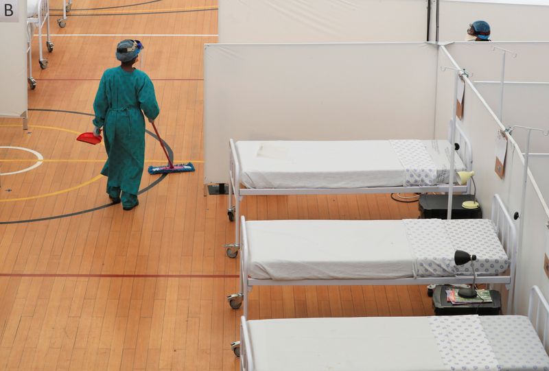 A health worker walks between beds at a temporary field
