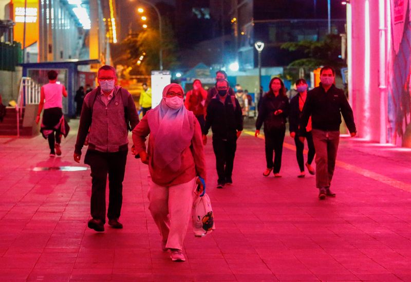 People wearing protective face masks walk during rush hour amid