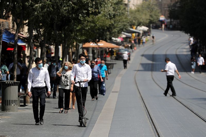 People wear protective masks as they walk around central Jerusalem