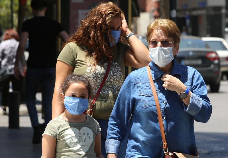 People wearing protective face masks walk along a street in