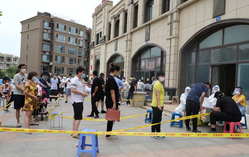 FILE PHOTO: Residents wearing face masks line up to receive