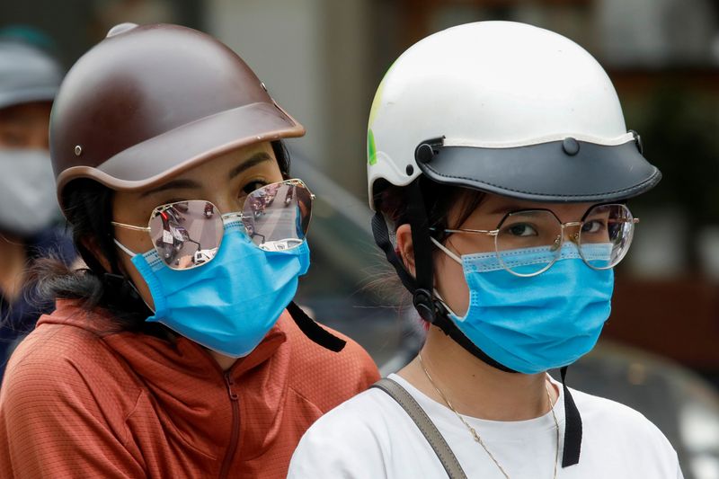 Women wear protective masks as they ride in a street