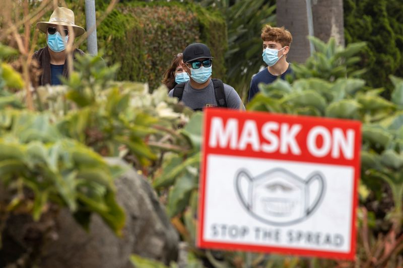 FILE PHOTO: People wear masks as they walk along the