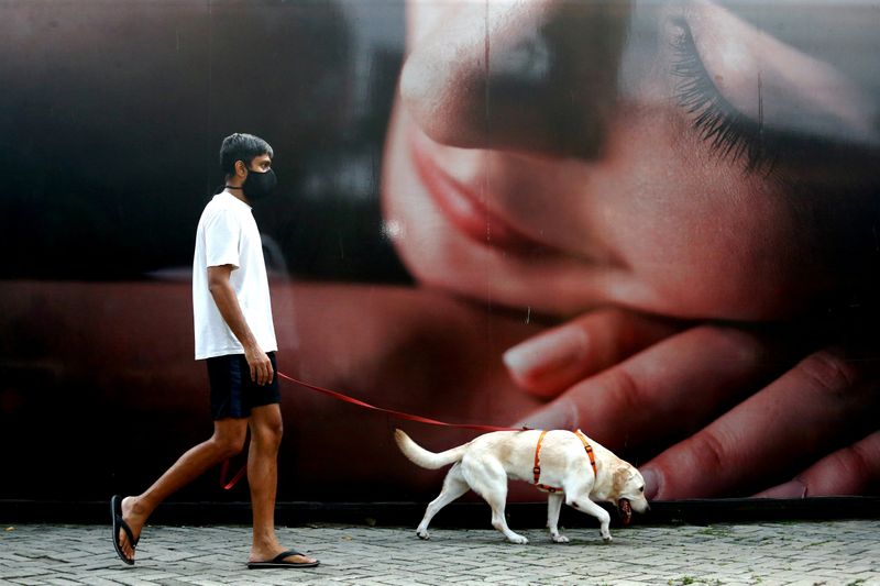 A man wearing a face mask walks with his dog