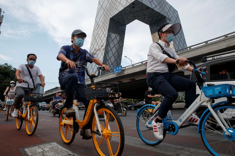 FILE PHOTO: People ride shared bicycles past the CCTV headquarters