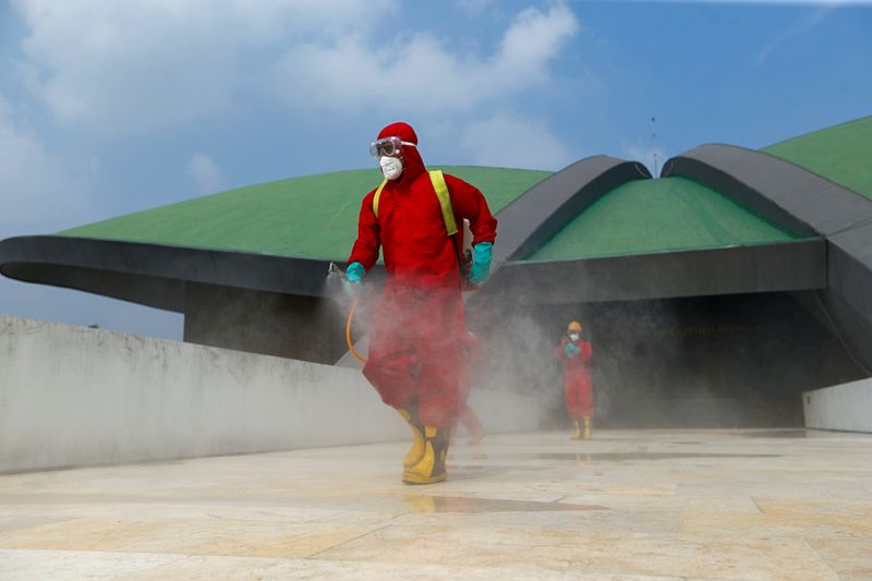Firefighters wearing protective suits spray disinfectant in the Indonesian Parliament