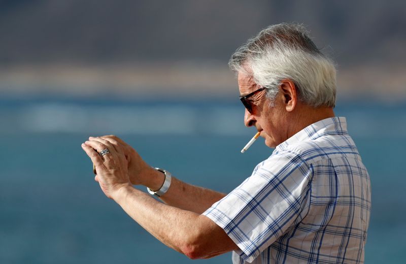 A man smokes a cigarette while taking a picture with