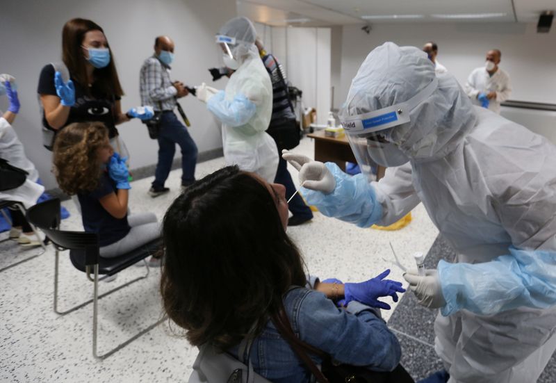 Health workers take swab samples from passengers who arrived at