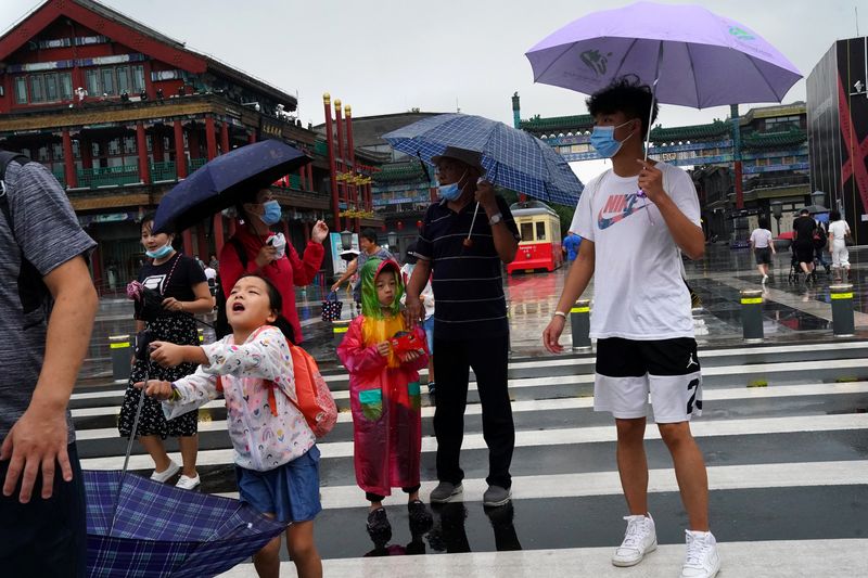 People wearing face masks walk near Qianmen Street on a