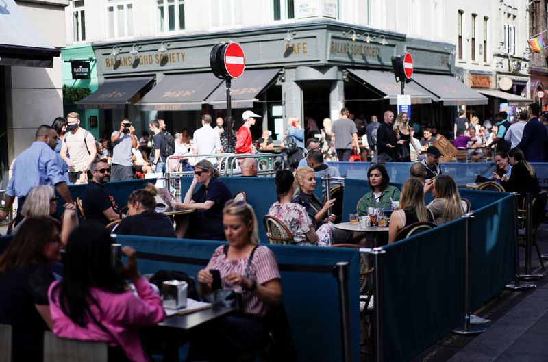 People sit at the tables outside restaurants in Soho, amid