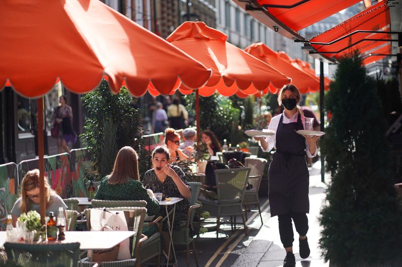 People sit at tables outside restaurants in Soho, amid the