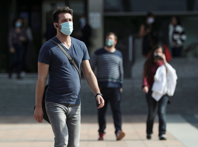 People wearing protective masks walk past the European Parliament headquarters