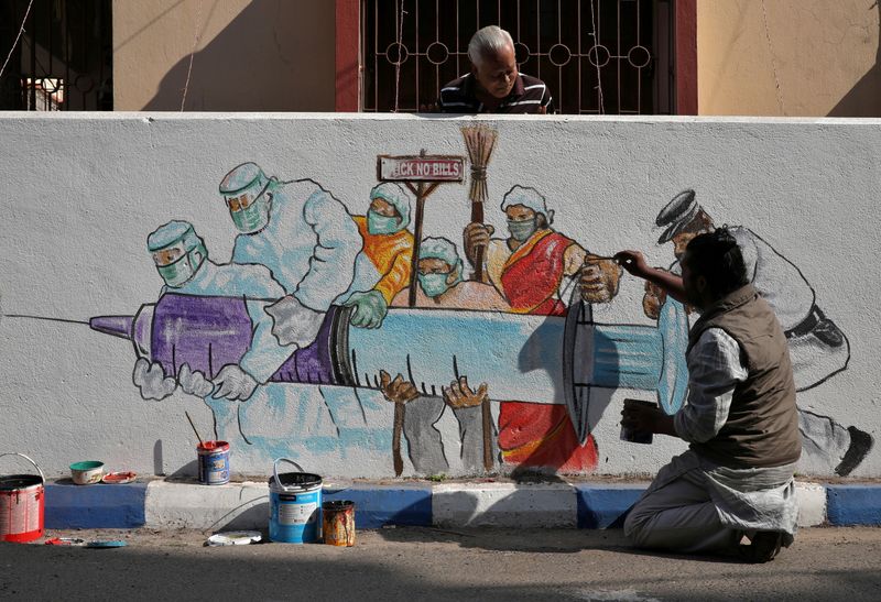 Man applies finishing touches to graffiti representing a vaccine in