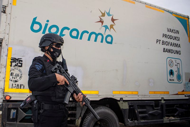 An armed police officer stands guard next to a truck