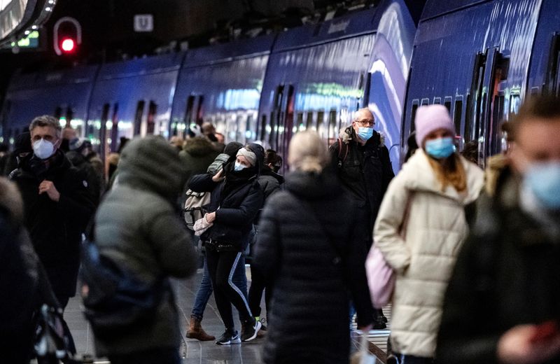 Passengers wearing protective masks walk on a platform at Malmo
