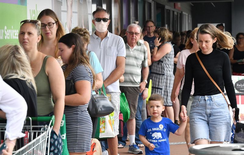 People line up to enter a grocery store before an