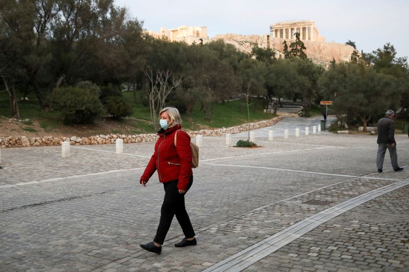 FILE PHOTO: A woman wearing a protective mask walks down