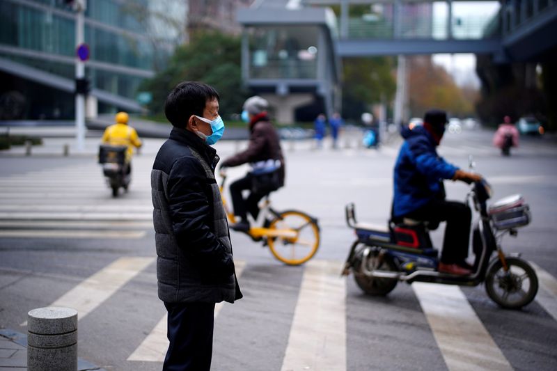FILE PHOTO: Man wearing a mask stands near a street,