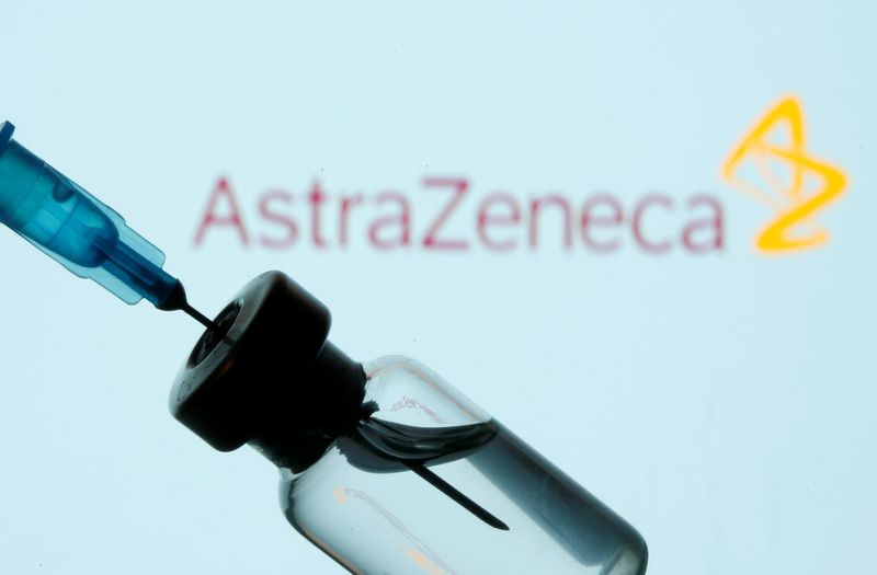 Vial and sryinge are seen in front of displayed AstraZeneca