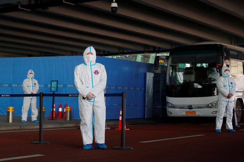 Staff members in protective suits stand guard next to a