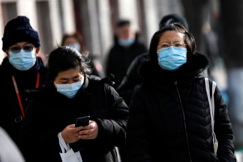 People wearing masks walk on a street, following the new
