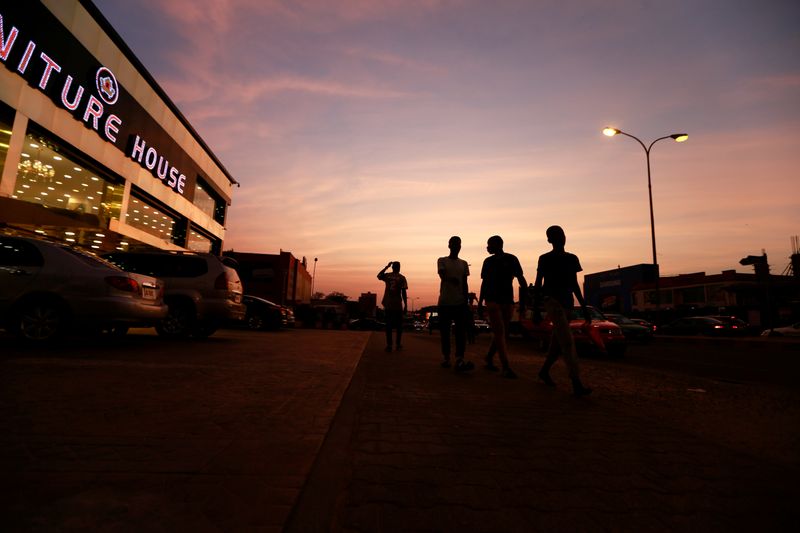 FILE PHOTO: People are seen walking at sunset pass a