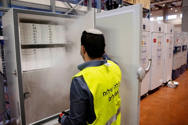 An employee opens a freezer containing Pfizer’s vaccination against the