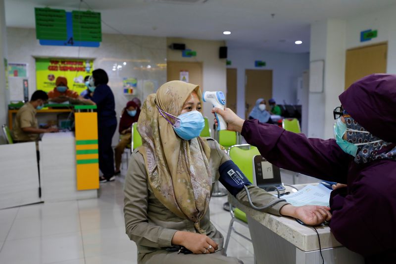 An Indonesian doctor has a temperature check at a district